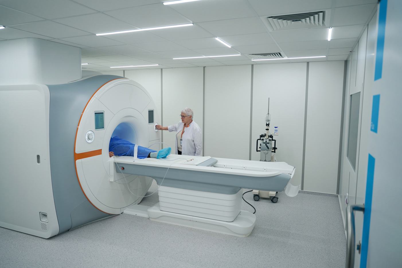 Elderly diagnostician examines a patient on an MRI machine