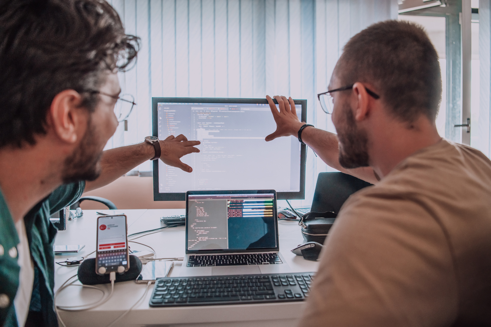 Programmers engrossed in deep collaboration, diligently working together to solve complex problems and develop innovative mobile applications with seamless functionality.